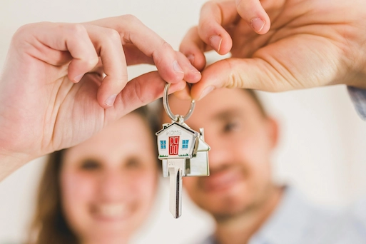 Dos personas sostienen unas llaves de casa en símbolo de colaboración inmobiliaria.